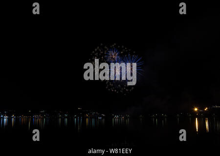 Bacoli, Napoli, 6 agosto 2019. I fuochi d'artificio dipingono il cielo in vari colori e sono riflesse nel lago Miseno, creando un panorama mozzafiato. Foto Stock