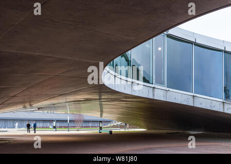 Esterno al piano terra della Rolex Learning Center (EPFL) con calcestruzzo affascinano ondulata di pavimento forato e tetto con facciata di vetro. Foto Stock