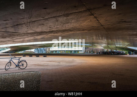 Esterno al piano terra della Rolex Learning Center (EPFL) con calcestruzzo affascinano ondulata di pavimento forato e tetto con facciata di vetro. Foto Stock