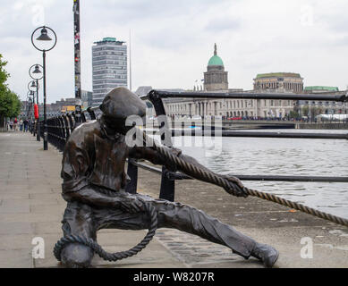 Dony McManus la scultura del per guardafili in City Quay, Dublin, con il Customs House e la Liberty Hall in background. Foto Stock