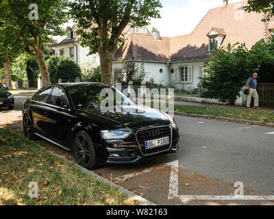 Kehl, Germania - Luglio 14, 2017: nero di lusso Audi auto parcheggiata su una strada tedesco con bella casa in background e maschi adulti passeggiate pedonali Foto Stock