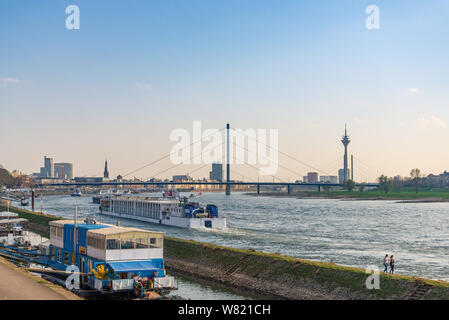 Outdoor sunny view di persone a piedi sul molo e ancoraggio barche al molo lungo il fiume Reno sullo sfondo di barca a vela e il paesaggio urbano del centro. Foto Stock