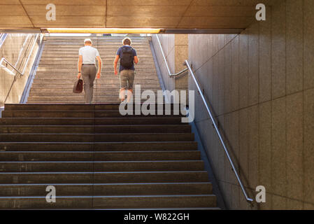 Basso angolo di visione con il sole splendente luce dorata, 2 mens a piedi dalla stazione della metropolitana attraverso pubblico scala per outdoor city upstair. Foto Stock
