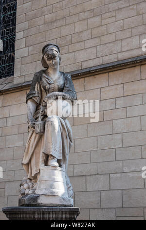 Bruxelles, Belgio - 22 Giugno 2019: Closeup di Beige statua di pietra con la muffa nera del Milkmaid, servendo il latte al di fuori della caraffa beige contro il muro di pietra di Foto Stock