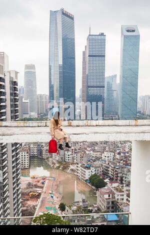 Un modello pone contro le vecchie case residenziali in Xiancun village, che è in fase di ristrutturazione, circondato da un alto edificio nella città di Guangzhou, s Foto Stock