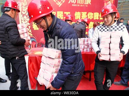 Cinese i lavoratori migranti ottenere fasci di 100-yuan RMB (Renminbi) banconote per i loro stipendi e premi di fine anno presso il cantiere per la costruzione di una vera e propria es Foto Stock