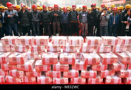 Fasci di 100-yuan RMB (Renminbi) banconote per stipendi e premi di fine anno dei lavoratori migranti sono impilati fino al luogo di costruzione di una vera e propria es Foto Stock