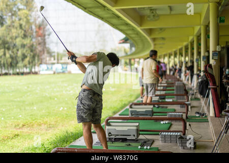 L'uomo mettere in pratica i suoi golf swing a golf driving range. Foto Stock