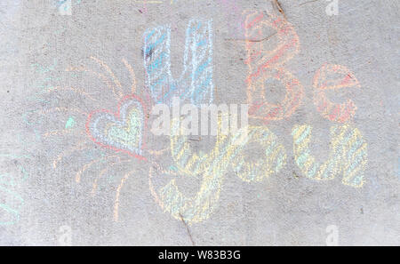 Le parole 'U' scritto con sidewalk chalk sul cemento grigio Sfondo marciapiede Foto Stock