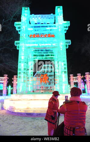 Visitatori posano per le foto di fronte a sculture di ghiaccio durante la xliii Ice-lantern Festival nella città di Harbin, a nord-est della Cina di Provincia di Heilongjiang, 26 D Foto Stock