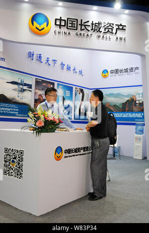 --FILE--un dipendente cinese di colloqui con un visitatore presso lo stand di China Great Wall Asset Management Corporation nel corso di una mostra a Shanghai in Cina, Foto Stock