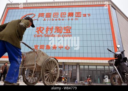 --FILE--un lavoratore cinese cammina davanti a un centro di servizio di cun.taobao.com, cinese di e-commerce Alibaba del servizio di shopping per le zone rurali, nel conteggio Yiyang Foto Stock