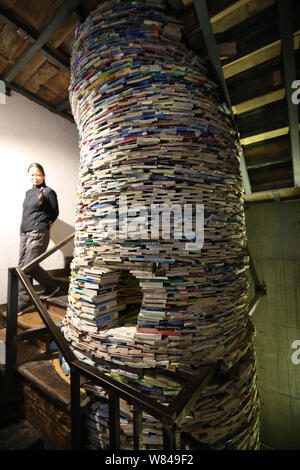 Una donna guarda una ben conformato installazione composta di libri scartati da madre cinese per ricordare la figlia di mai la lettura di libri meccanicamente a Foto Stock