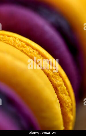 Macro dettaglio di una pila di giallo e viola amaretti francese. Molto leggera profondità di campo, il fuoco selettivo su giallo macaron. Cookie sfondo verticale Foto Stock