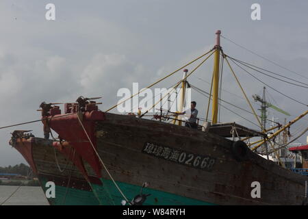 Un pescatore cinese si lega a una barca da pesca in fase di preparazione per il Tifone Sarika presso un porto nella città Qionghai, Cina del sud della provincia di Hainan, 15 ottobre 2 Foto Stock