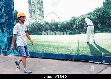--FILE--un cinese lavoratore migrante passeggiate passato un tabellone presso il cantiere per la costruzione di un complesso residenziale progetto immobiliare a Shanghai in Cina, 3 agosto 2016. Foto Stock