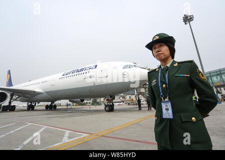 --FILE--femmina di un funzionario di polizia sta di guardia accanto a un piano a getto di Lufthansa a Qingdao Liuting International Airport nella città di Qingdao, Cina orientale Foto Stock