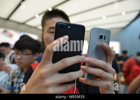 Una shopper confronta un iPhone 7 Plus con il suo Samsung smartphone a un Apple Sotre nella città di Nanjing East cinese della provincia di Jiangsu, 16 settembre 2016. Foto Stock
