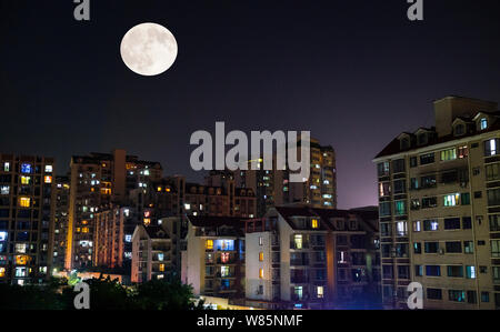 La luna piena sorge oltre il grattacielo di edifici residenziali a Chongqing Cina, 16 settembre 2016. Foto Stock