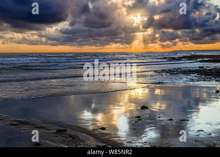 Un bellissimo tramonto a Dunraven Bay in Glamorgan Heritage Coast, nel Galles del Sud, con stupende riflessioni cloud nella sabbia bagnata. Foto Stock