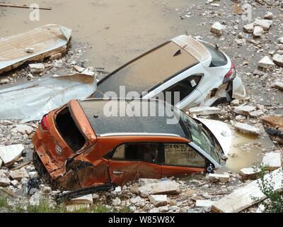 Le automobili private sono immerse in acqua dopo essere stata lavata da inondazioni causate da un acquazzone in una buca dal parcheggio in un quartiere residenziale in Foto Stock