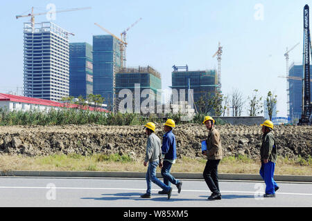 --FILE--cinese lavoratori migranti a piedi passato un progetto immobiliare in corso di costruzione a Suzhou City, est cinese della provincia di Jiangsu, 17 ottobre 2015. T Foto Stock