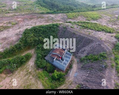 Un chiodo casa il cui proprietario ha rifiutato di spostare a causa di dispute sui dettagli di compensazione è isolato in una fossa presso il cantiere per la costruzione di un settore industriale Foto Stock