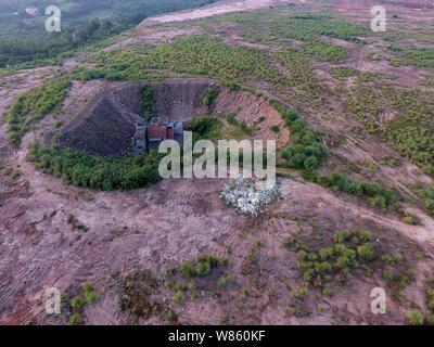 Un chiodo casa il cui proprietario ha rifiutato di spostare a causa di dispute sui dettagli di compensazione è isolato in una fossa presso il cantiere per la costruzione di un settore industriale Foto Stock