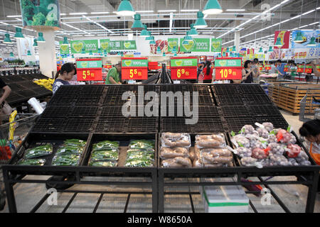 Gli acquirenti cinesi a piedi passato quasi vuota ripiani vegetale in un supermercato prima della venuta di tifone Nida nella città di Shenzhen, sud cinese di Guangdong Foto Stock