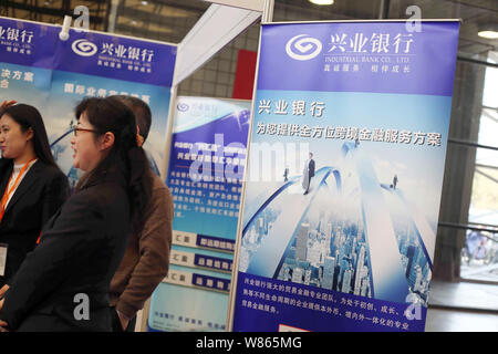 --FILE--dipendenti cinesi parla con i visitatori allo stand della banca industriale Co., Ltd. durante una mostra a Shanghai in Cina, 1 marzo 2016. Industr Foto Stock