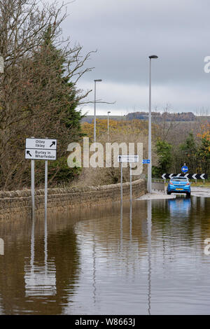 Allagamento - allagato strade carrozzabili (auto parcheggiate) e profondità acqua di inondazione rendendo la guida pericolosa - Burley in Wharfedale, nello Yorkshire, Inghilterra, Regno Unito Foto Stock