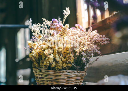 Chiudere antiche essiccato mazzo di fiori in cesto in legno con una luce calda spazio copia, concetto di memoria Foto Stock