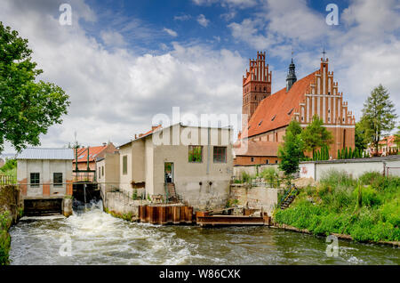 Dobré Miasto, ger. Guttstadt, warmian-mazurian provincia, Polonia. Piccola centrale idroelettrica. In background - XIV sec. collegiata. Foto Stock