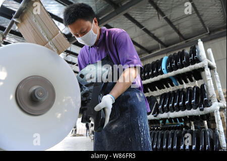 --FILE--un lavoratore cinese lucidi di una chitarra in una fabbrica nella città di Huainan, est cinese della provincia di Anhui, 16 maggio 2016. Il Caixin generale manufatto Cina Foto Stock