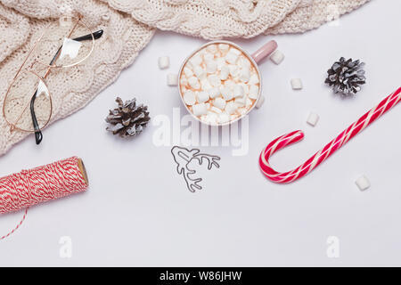 Composizione di natale con il cacao, marshmallows, felpa lavorata a maglia e altri oggetti tradizionali sullo sfondo bianco, vista dall'alto Foto Stock