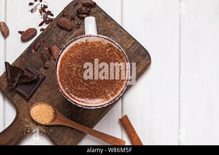 Cioccolata in tazza, le fave di cacao e polvere sul bianco tavolo in legno, vista dall'alto Foto Stock