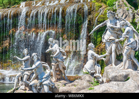 23 giugno 2019 / CASERTA, ITALIA: Un gruppo di statue di fronte ad una cascata in splendidi giardini della Reggia di Caserta in Italia. Foto Stock