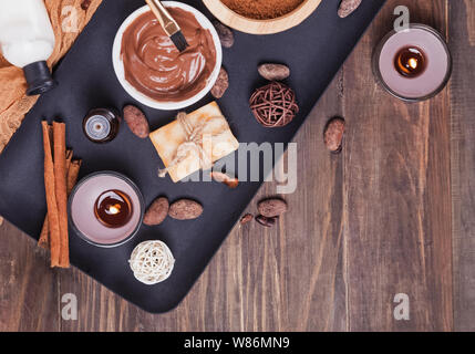 Il cioccolato spa impostato sullo sfondo di legno, vista dall'alto. Cura del corpo essentials, oli aromatici e altri Foto Stock