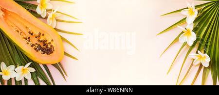 Creative composizione estiva con foglie di palma, papaia e plumeria fiori. Sfondo tropicale. Foto Stock