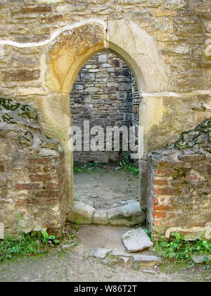 Lo stile gotico portal tra muri di pietra e mattoni. Nel cortile interno della fortezza di Suceava ci sono molto spesse mura Foto Stock