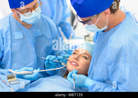 Dentista medico e la sua squadra per trattare un paziente presso la clinica Foto Stock