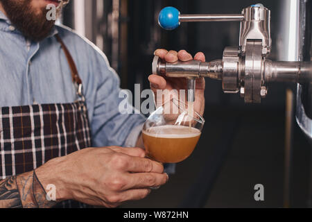 Close up di un bicchiere di birra essendo riempito con baverage. Foto Stock