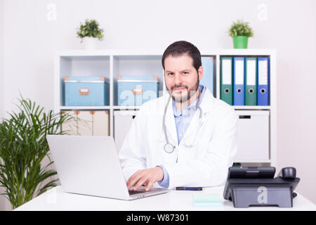 Barbuto medico che lavorava presso il suo ufficio. Business e concetto medico. Foto Stock