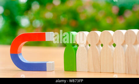 Figure in legno di persone e di un magnete. Gestione dei Team concetto. Risorse umane. Promuovere. La scelta di un nuovo leader e di assunzione dei dipendenti al lavoro. Headhunt Foto Stock