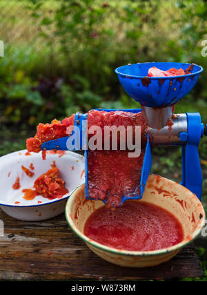 Vicino la foto di un manuale di pomodoro smerigliatrice. Pomodori freschi per la preparazione artigianale di pasta di pomodoro. Foto Stock