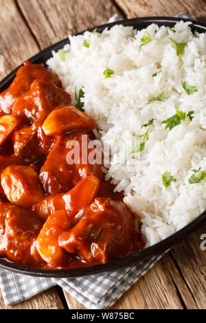 Marocchino stufato di manzo con mele con salsa di pomodoro fresco servito con riso closeup su una piastra sul piano verticale. Foto Stock