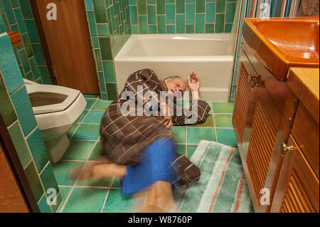 Anziani è sceso nel bagno quando scivolando sul tappeto allentati Foto Stock