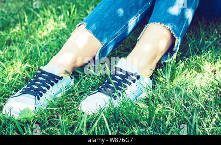 Giovane donna gambe nella coppia di scarpe sportive sneakers di blue suede sul prato in posizione di parcheggio Foto Stock