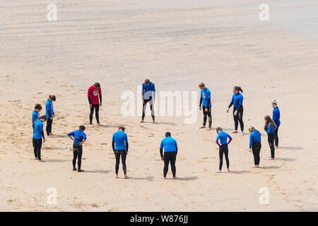 I surfisti principianti in fase di riscaldamento prima di una lezione di surf sulla grande Gt. Western Beach in Newquay in Cornovaglia. Foto Stock