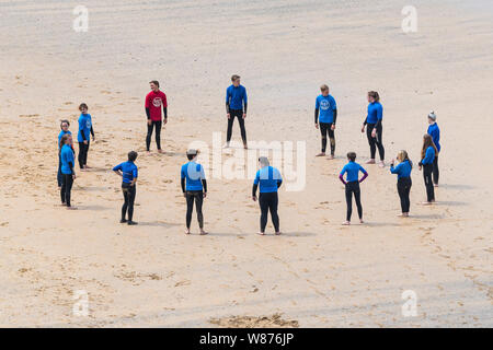 I surfisti principianti in fase di riscaldamento prima di una lezione di surf sulla grande Gt. Western Beach in Newquay in Cornovaglia. Foto Stock